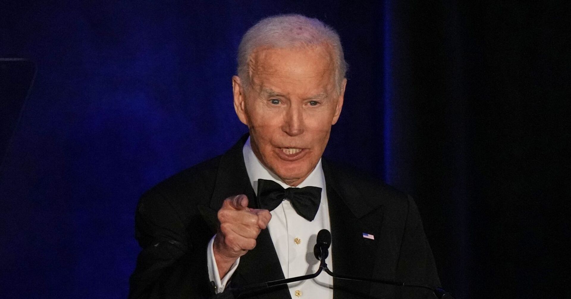 Joe Biden im schwarzen Smoking mit Fliege spricht bei einer Veranstaltung am Rednerpult und zeigt mit dem Finger nach vorne.