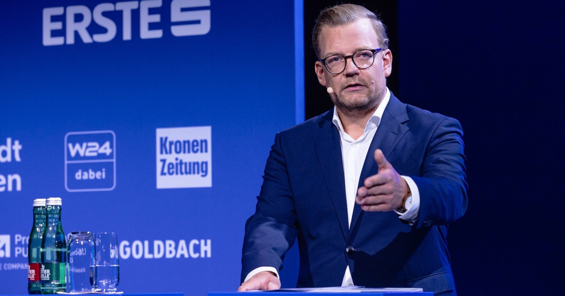 Jürgen Hofer im blauen Anzug vor einem blauen Hintergrund