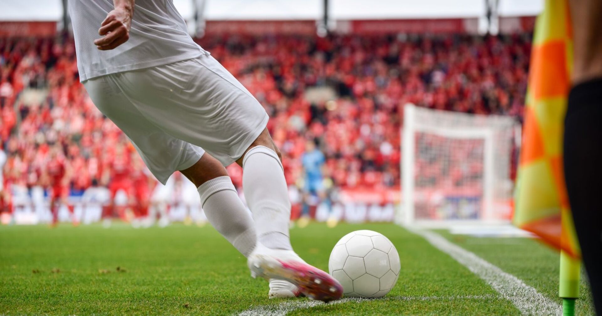 Fußballer welcher eine Ecke in einem vollen Stadion tritt