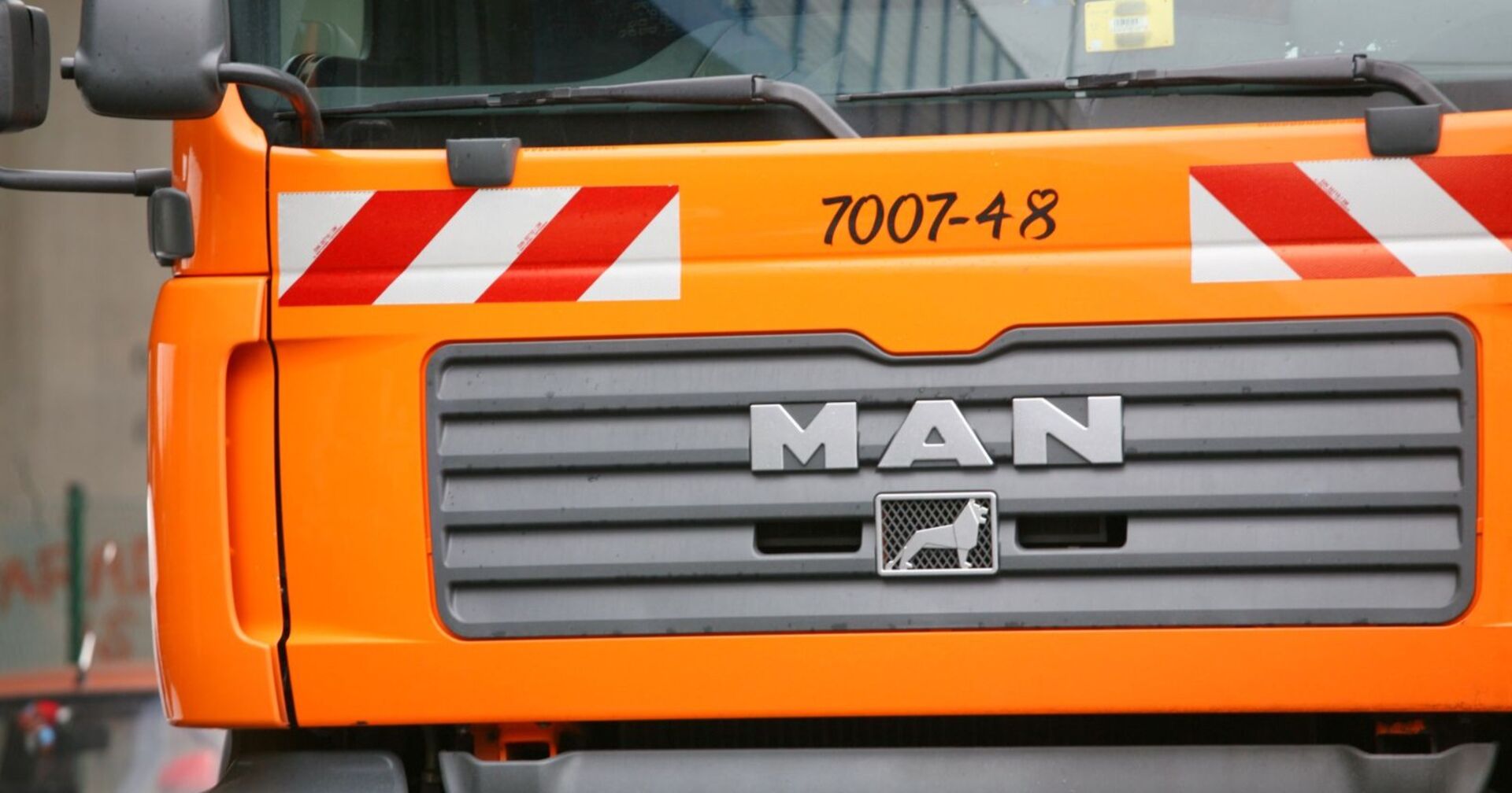 Orangefarbener Müllwagen der Stadt Wien, Nahaufnahme der Frontpartie mit MAN-Logo.