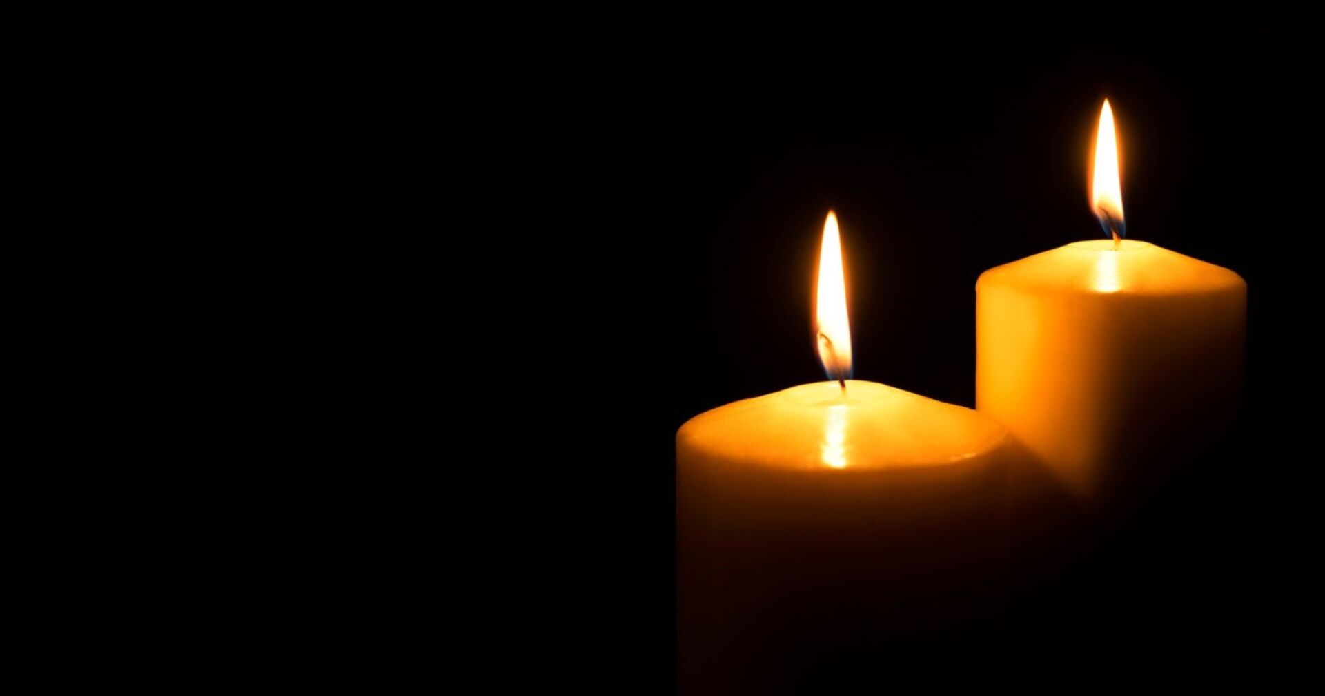 Brennende Kerzen vor schwarzem Hintergrund