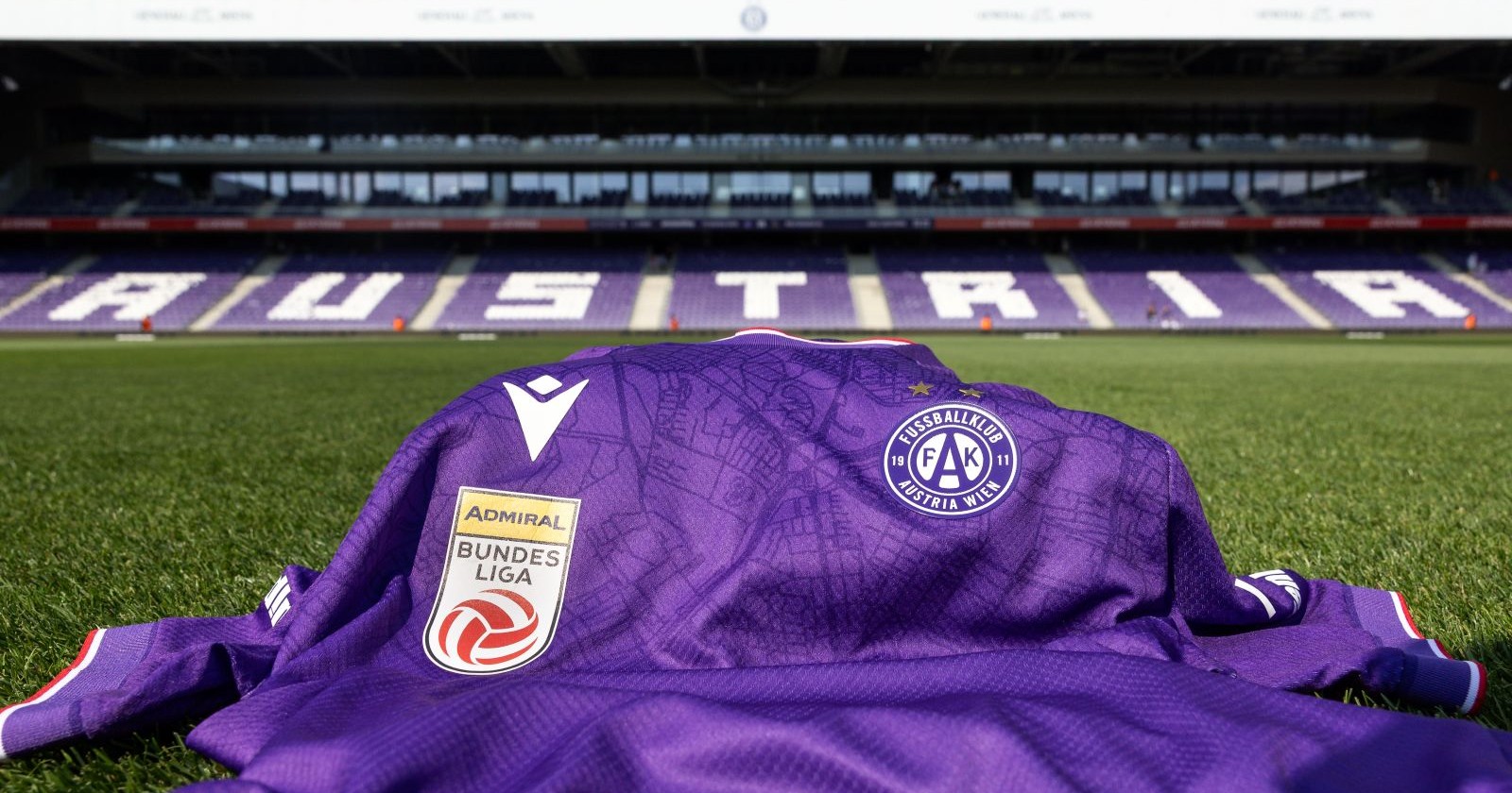 Trikot des FK Austria Wien auf dem Rasen der Generali Arena liegend, im Hintergrund eine Tribüne mit Austria-Schriftzug