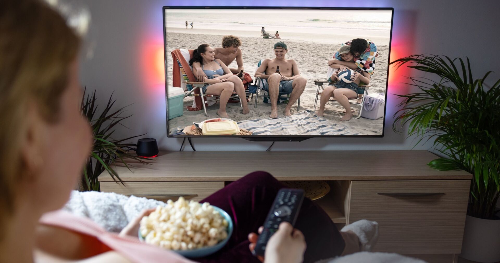 Eine Frau schaut Fernsehen und isst Popcorn