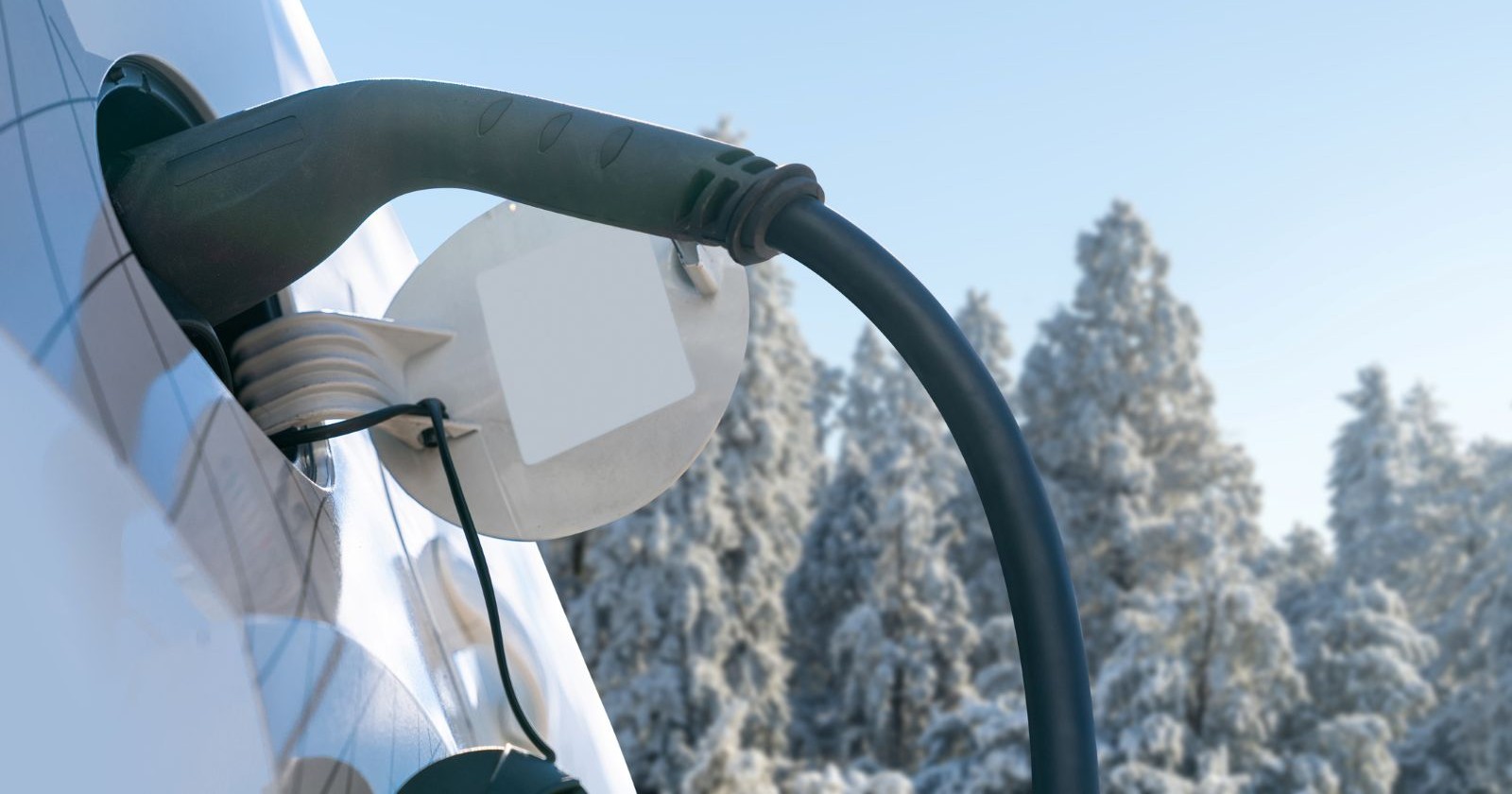 Nahaufnahme des Einlasses eines Elektroautos vor dem Hintergrund eines verschneiten Winterwaldes.