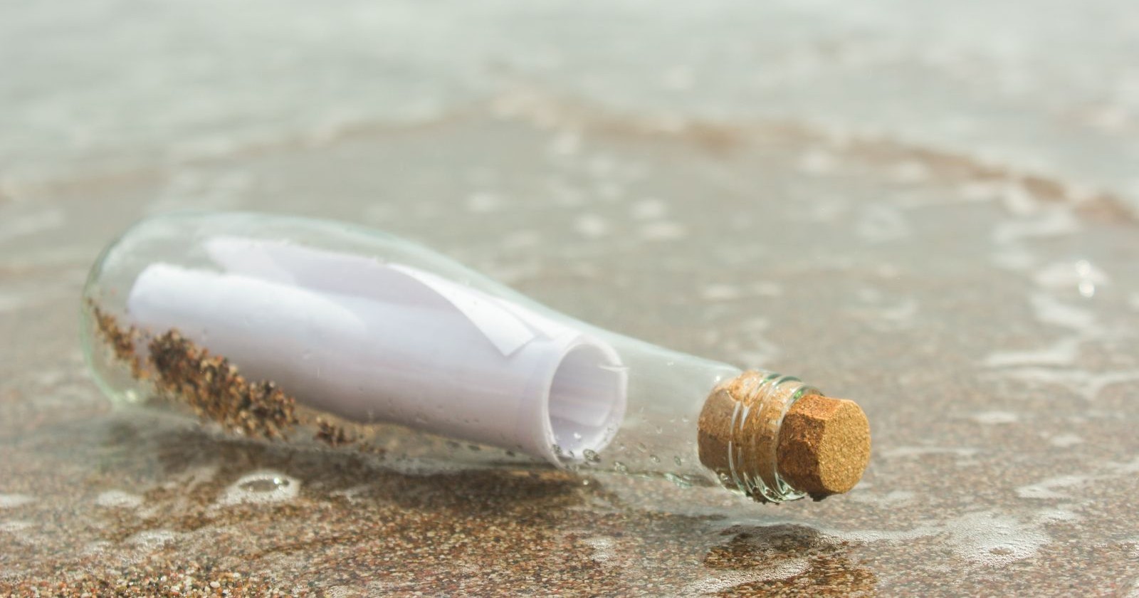 Flaschenpost mit eingerolltem Brief in einer Glasflasche, angespült am Strand von Wharton Beach in Australien.