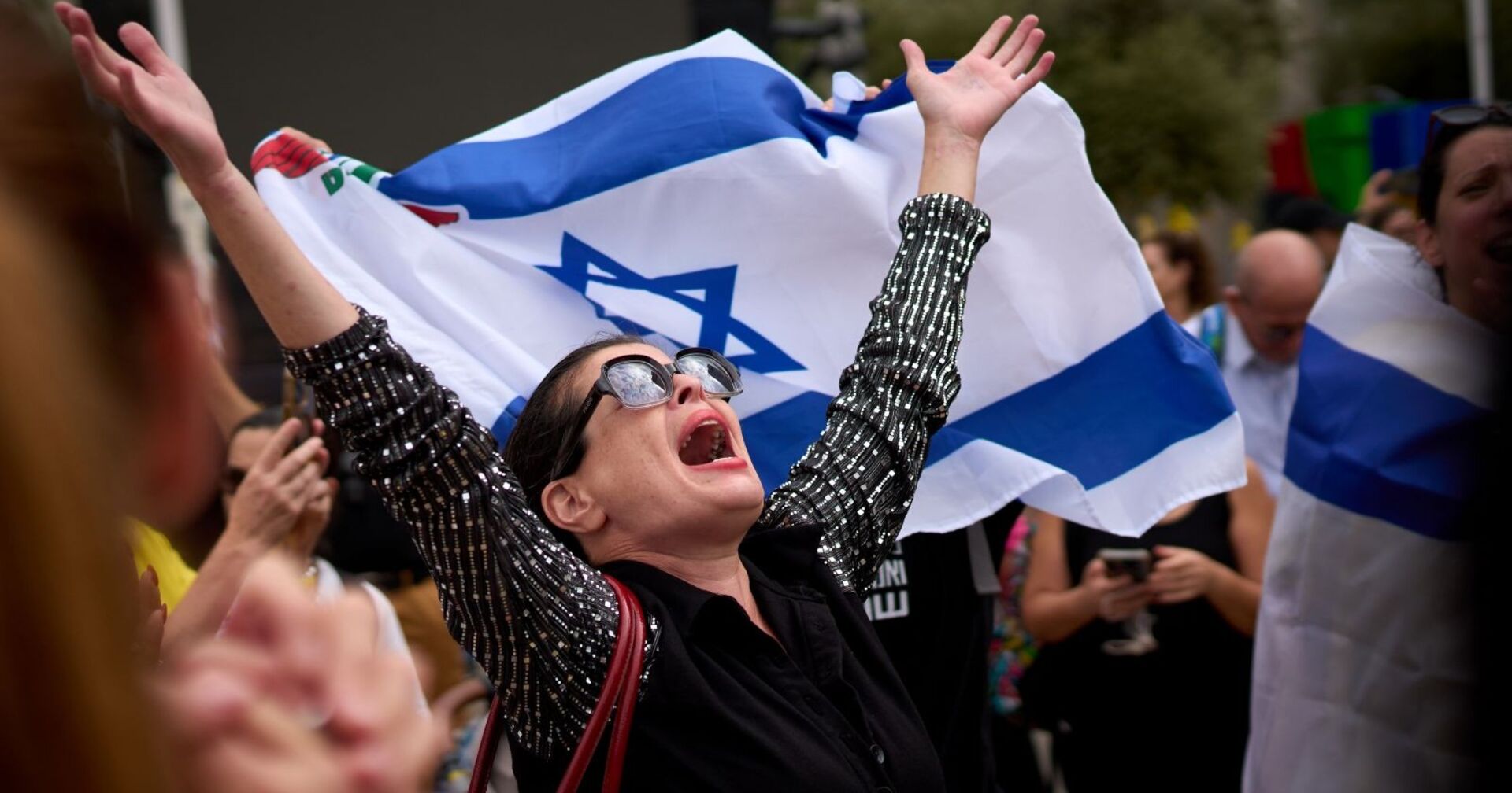 Frau jubelt mit israelischer Flagge in Tel Aviv nach der Einigung zwischen Israel und der Hamas auf eine Waffenruhe und einen Gefangenenaustausch.