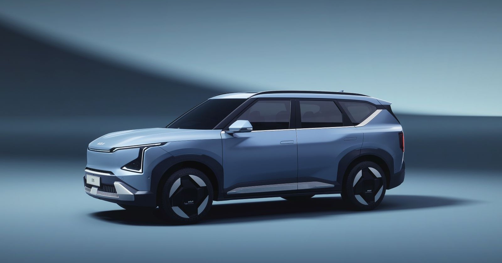 Ein hellblauer Kia EV5 in einem hellblauen Raum. Es sind sonst keine Möbelstücke oder Menschen zu sehen.