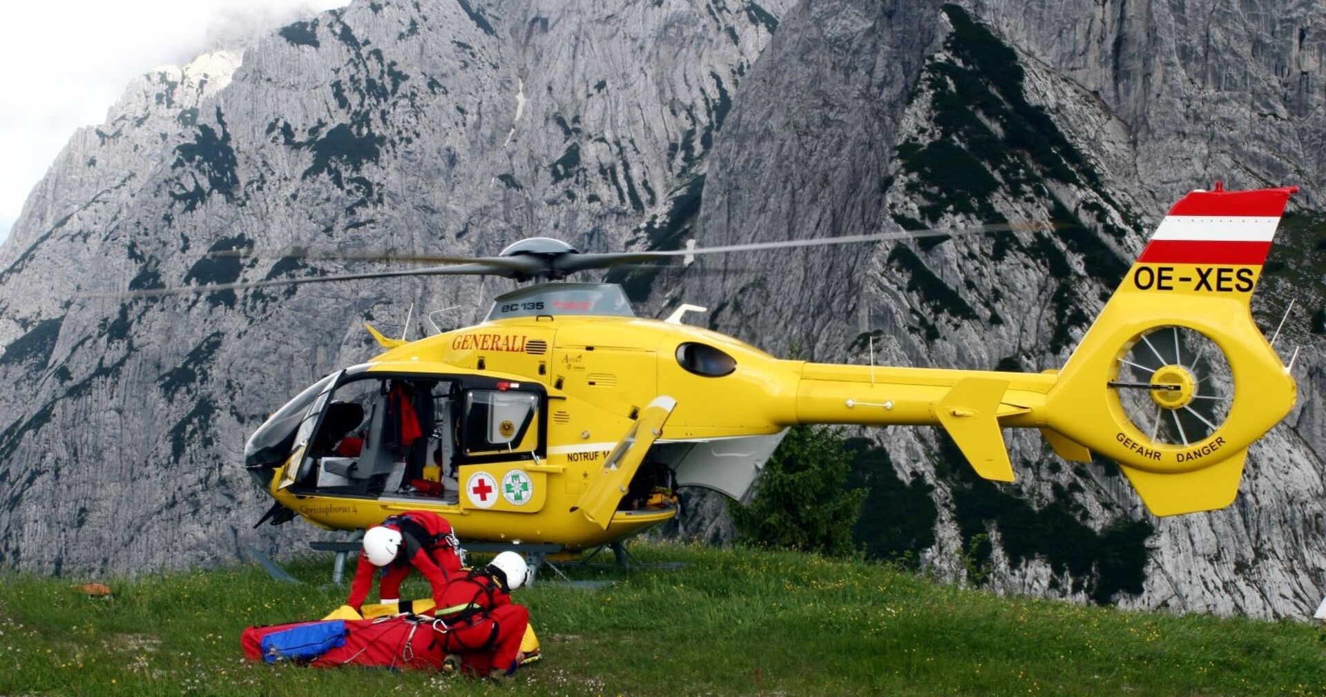 Rettungskräfte mit ÖAMTC-Hubschrauber bei einem Einsatz in den Bergen.