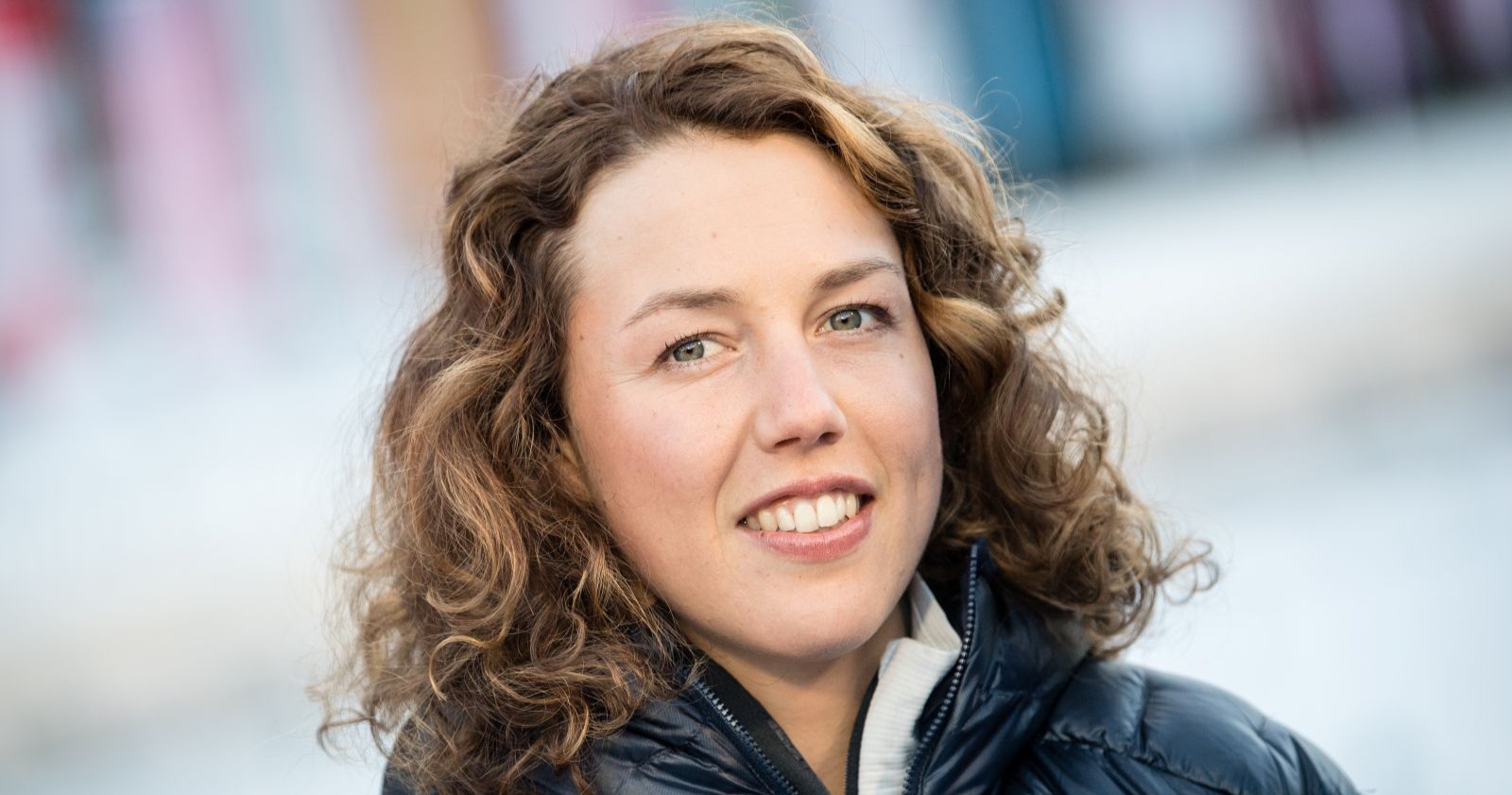 Laura Dahlmeier mit lockigen Haaren und Winterjacke im Freien, mit freundlichem Gesichtsausdruck.