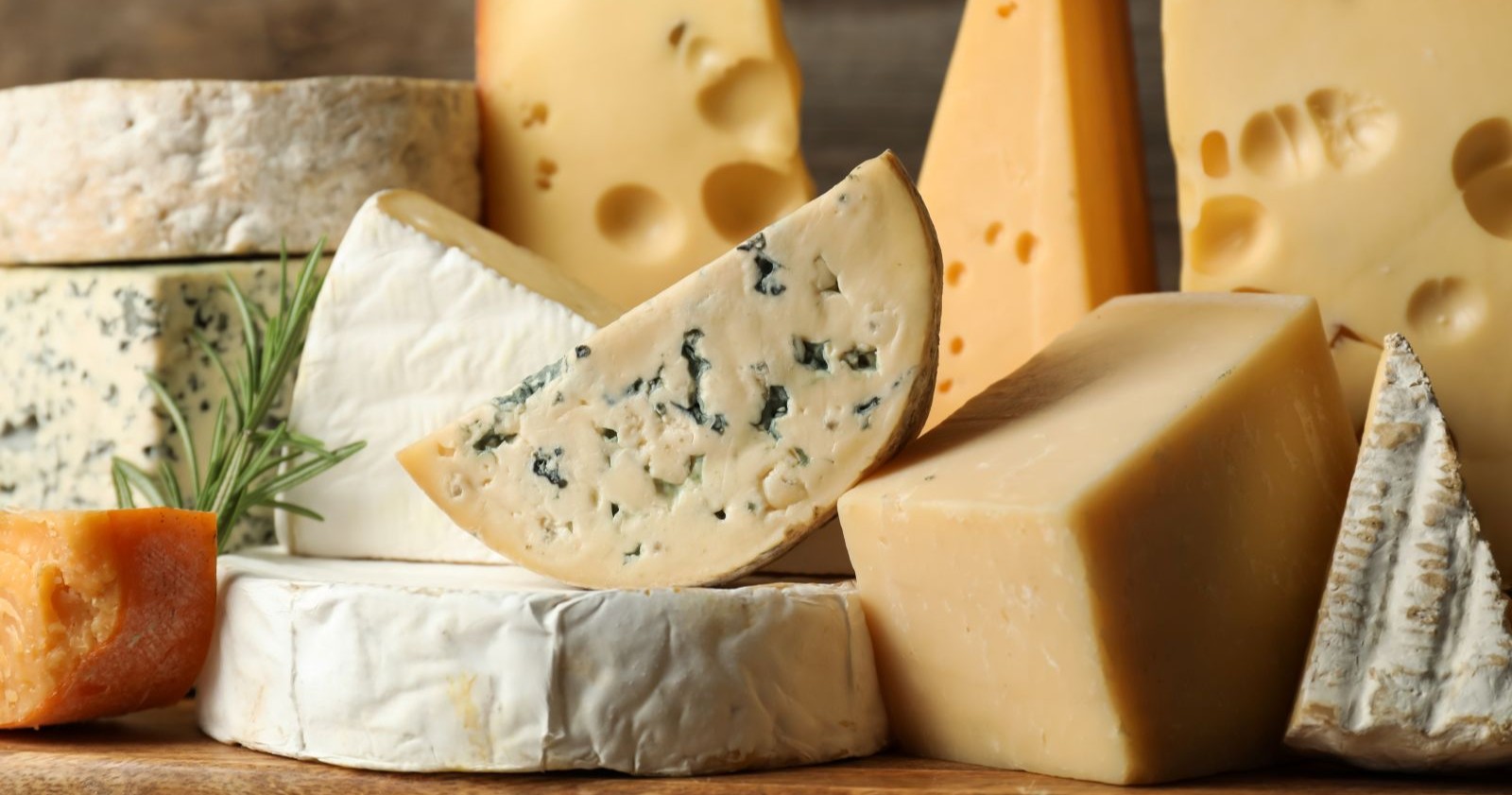 Mehrere Sorten Käse auf einem Holztisch, symbolisch für den aktuellen Metro-Rückruf von Raclette-Käse wegen Listerienverdachts.
