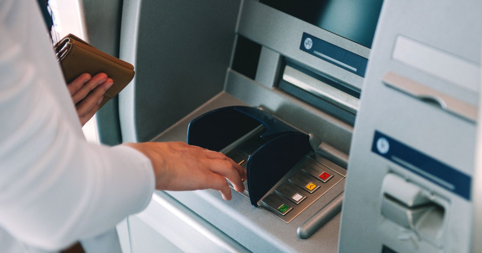 Frau an einem Bankomaten, die Geld beheben will