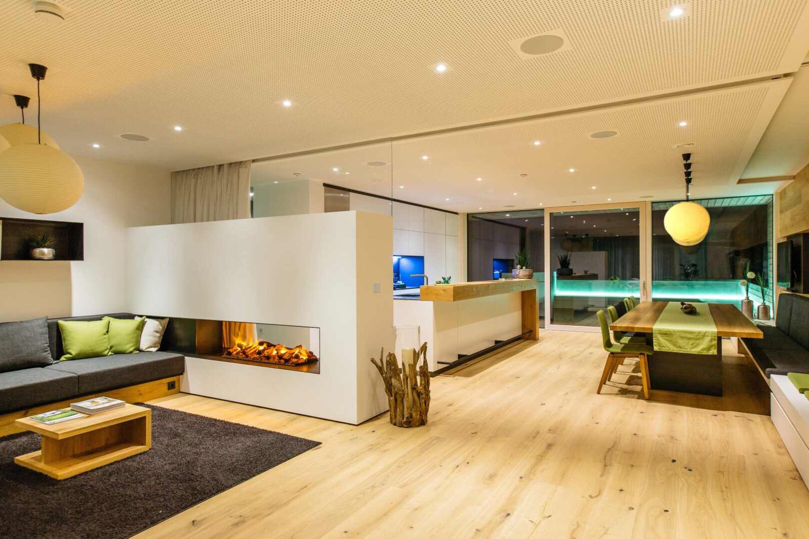 Modernes Wohn- und Esszimmer in einem Loxone Smart Home mit offenem Kamin, stilvoller Beleuchtung, Holzdesign und automatisierter Haussteuerung.