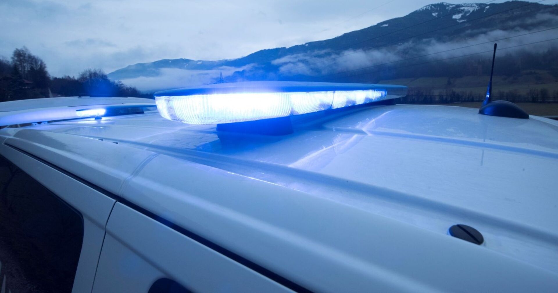 Blaulichtbetrieb eines Rettungsdienstes, Krankenwagen mit blauem Licht im Hintergrund steht einBerg