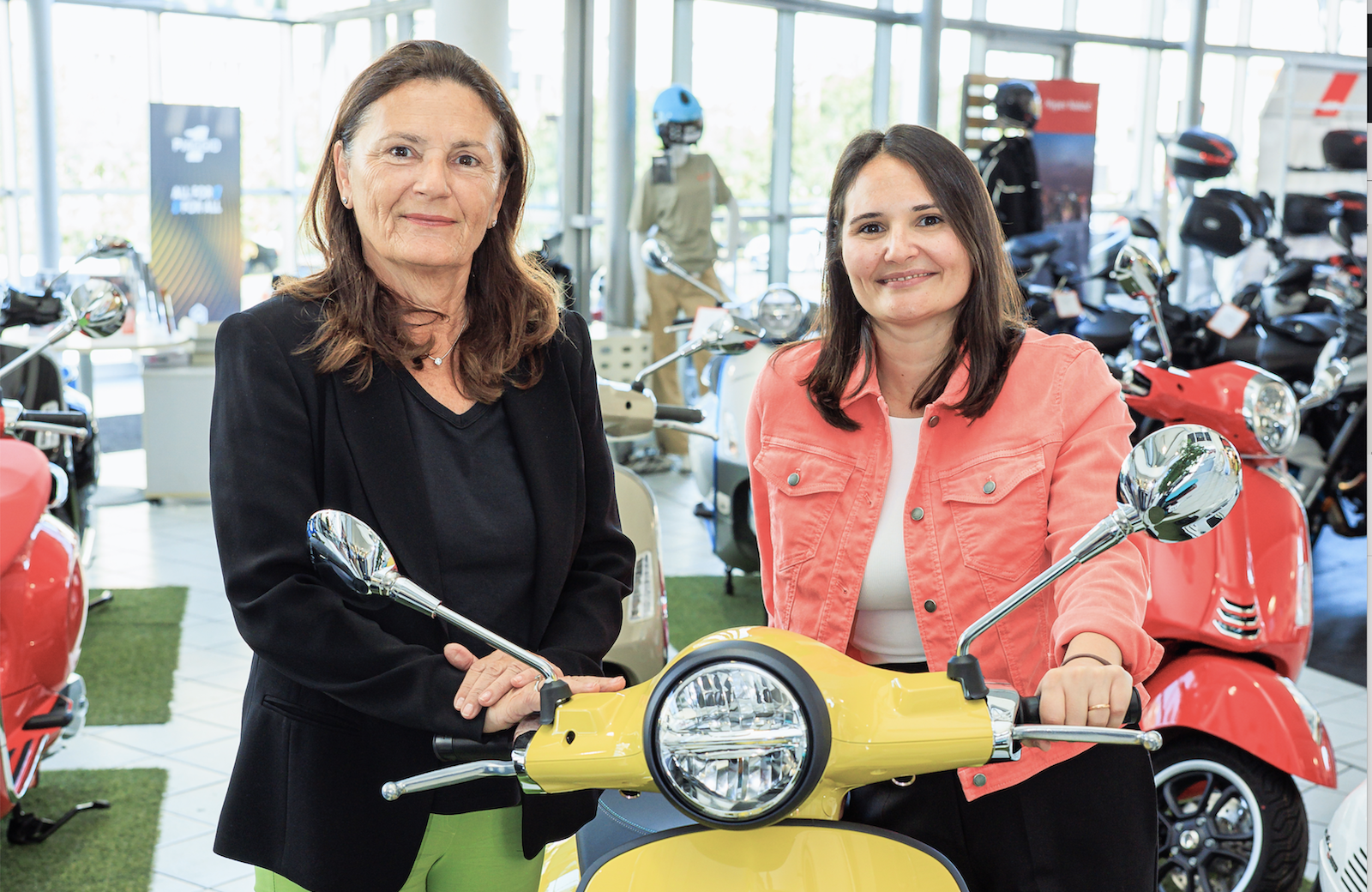 Porträt beider Frauen auf und neben gelber Vespa
