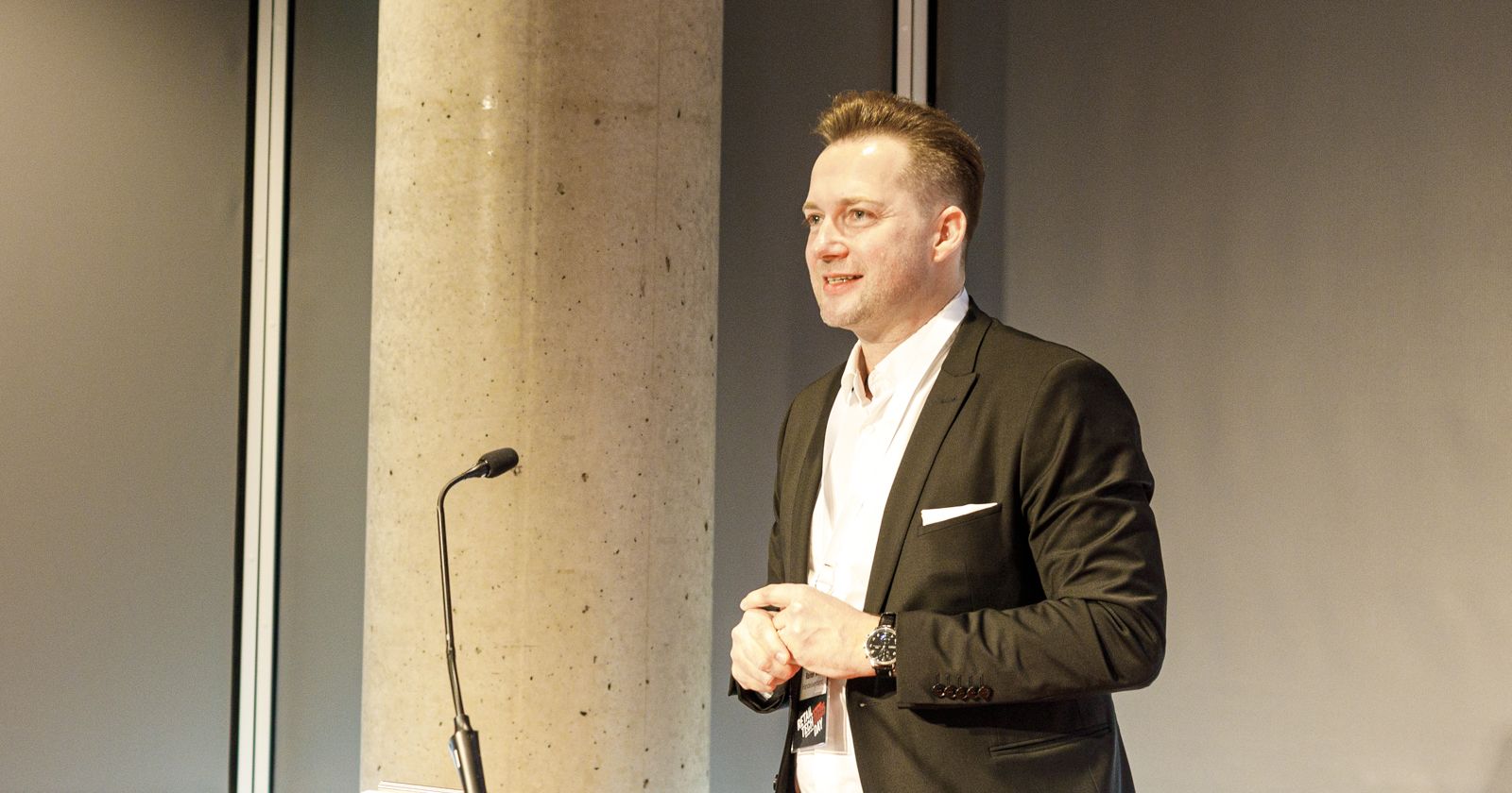 Rainer Will im weißen Hemd und dunklem Anzug spricht zum Publikum