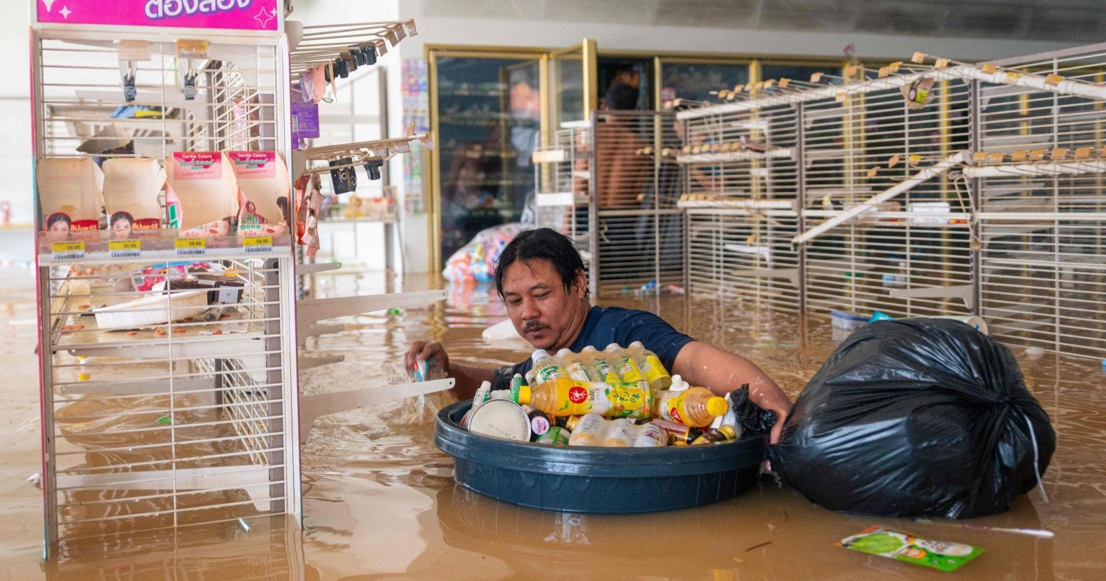 Mann watet durch überflutetes Geschäft in Hat Yai, Songkhla, Thailand – historische Überschwemmung nach Monsunregen 2025.