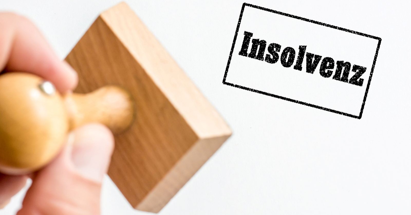 Nach Bild oder Video suchen Hand hält Stempel mit Stempel-Abdruck des deutschen Wortes Konkurs