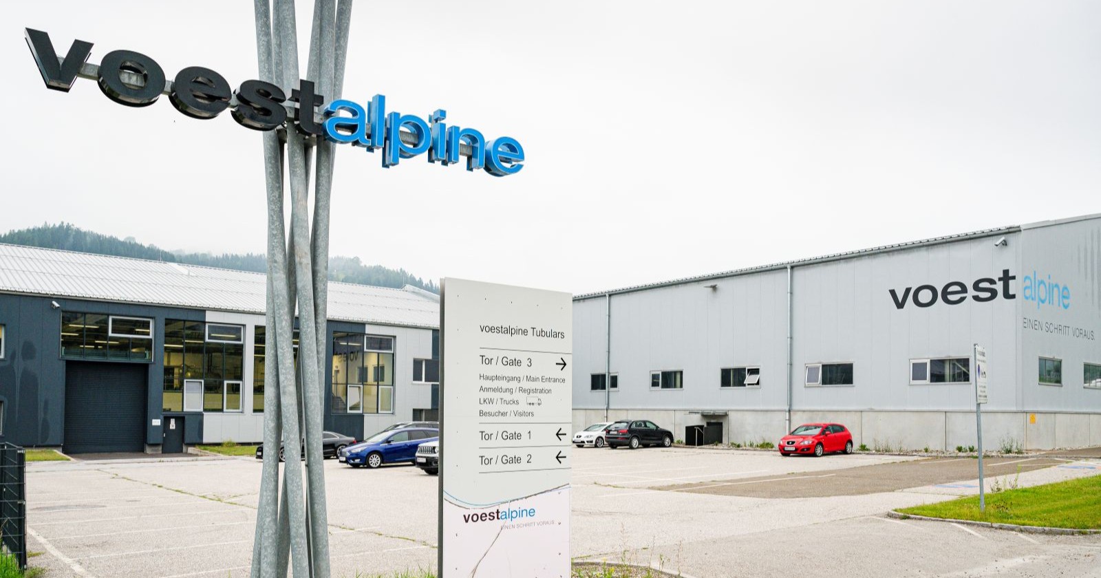 Voestalpine-Werk in Kindberg mit Firmenlogo und Parkplatz vor den Produktionshallen. Der Standort ist von den angekündigten Stellenkürzungen betroffen.