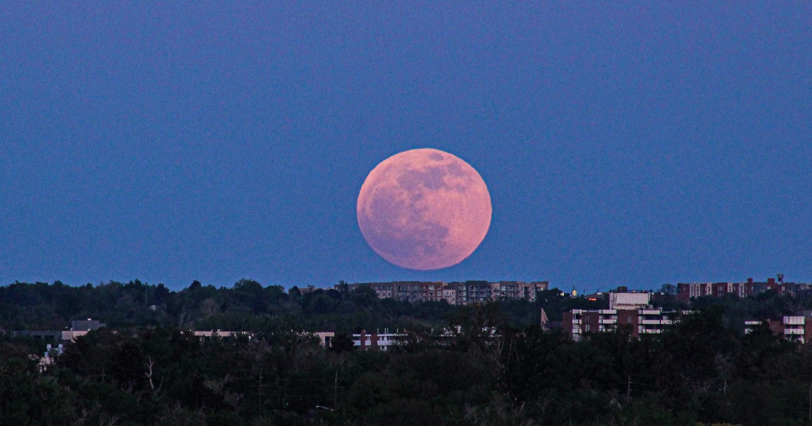 Vollmond über einer österreichischer Stadt bei Mondaufgang, im November geht ein Supermond über Österreich auf.