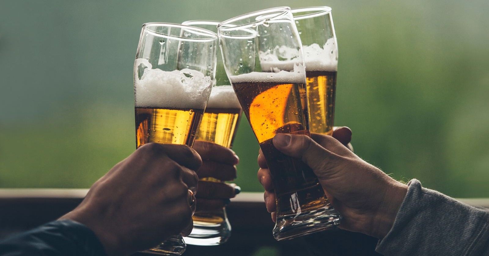 Bier mit schaumleichten großen Jungs in den Händen von Freunden, die einen Toast aus der Nähe anstoßen