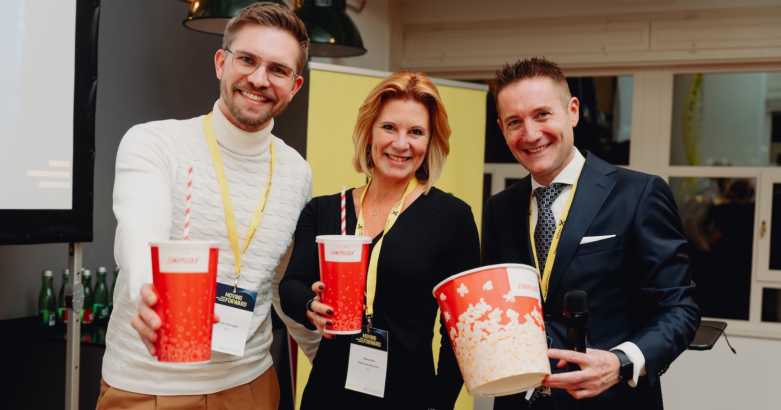 Zwei Männer und eine Frau mit Getränkebecher und Popcorn-Kübel