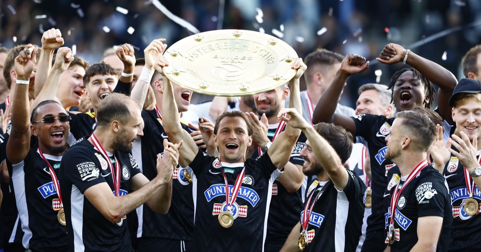 Die Mannschaft von Sk Sturm Graz feiert jubelnd und hält den Meisterteller in die Höhe.