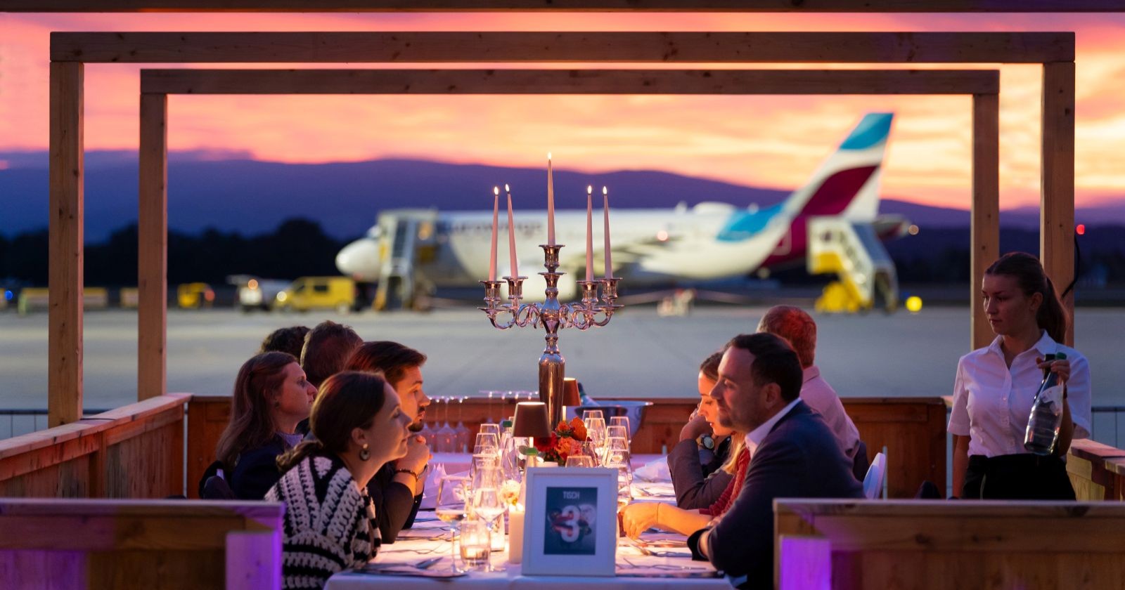 Mehrere Menschen dinieren vor einem Flugzeug