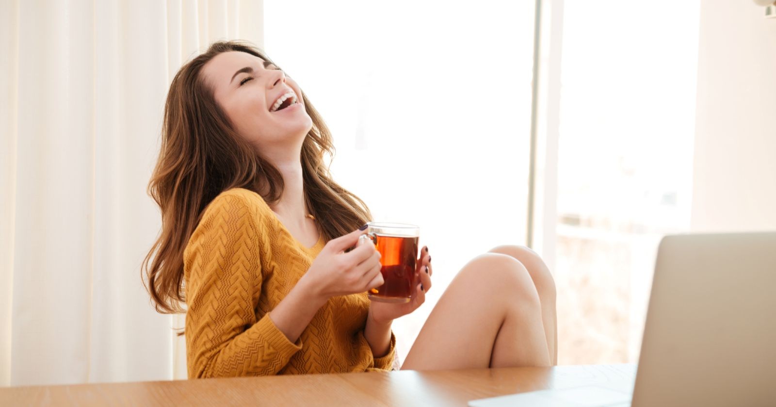 Eine Frau trinkt Tee und freut sich, sie wirkt glücklich - Symbolbild für Tipps, wie man seine Vorsätze einhält und Ziele erreicht.