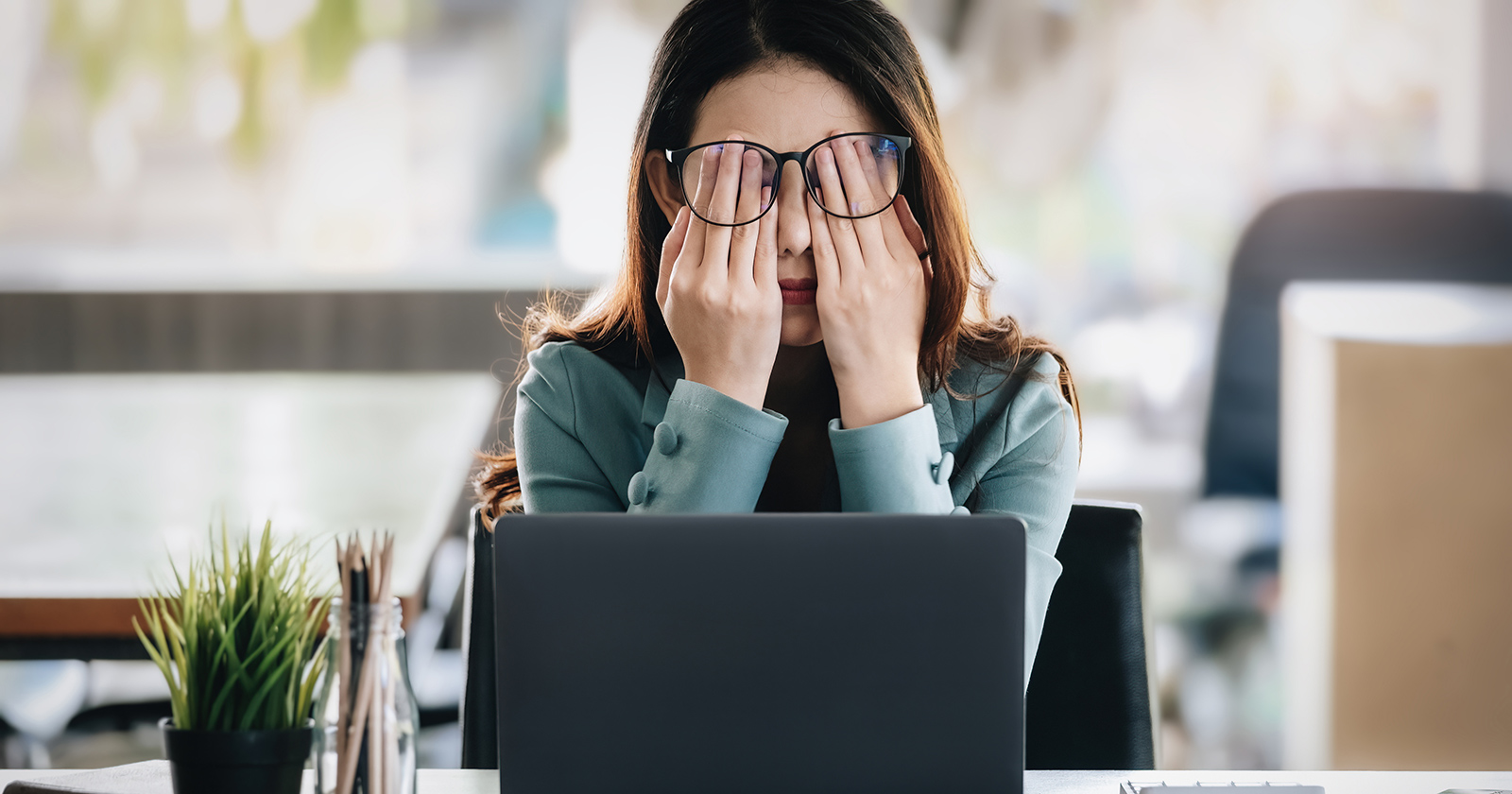 Frau hinter Notebook mit Händen vor ihren Augen | Credit: iStock.com/Jirapong Manustrong
