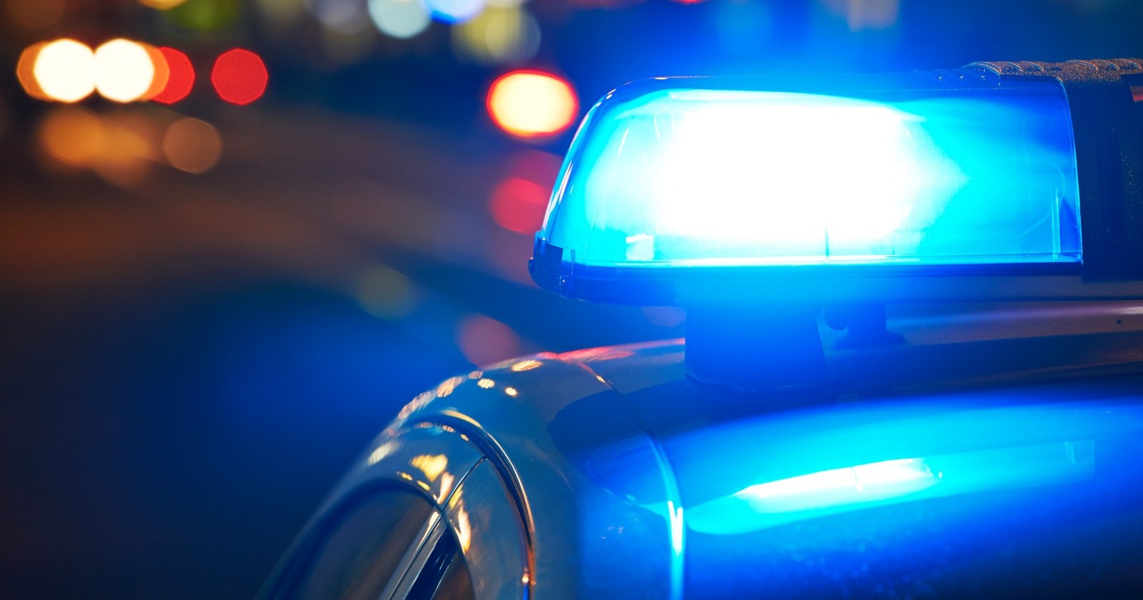 Eingeschaltete Blaulicht-Sirene eines Polizeiwagens bei Nacht