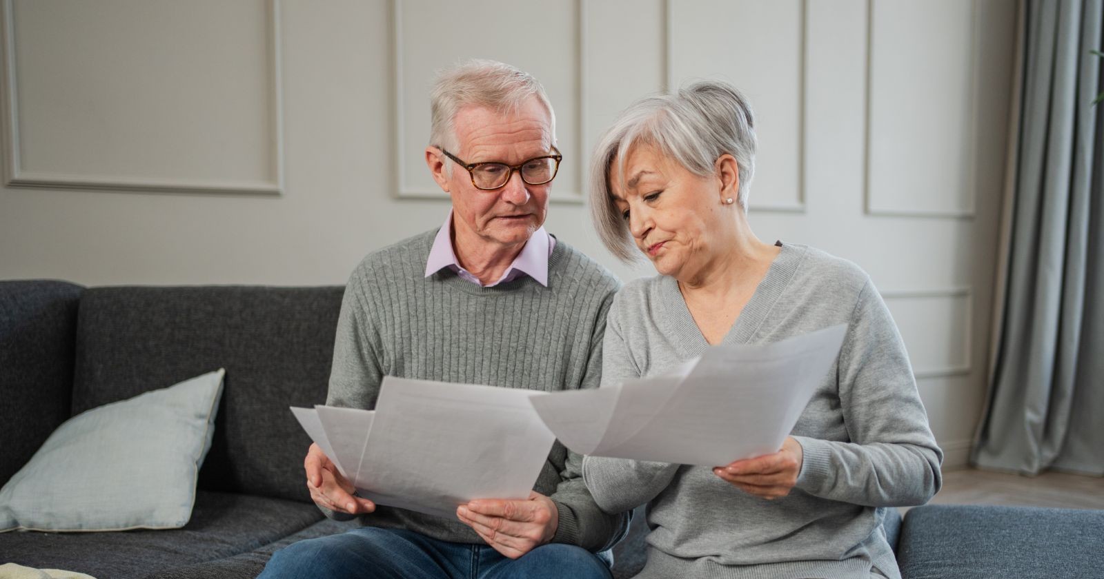 Älteres Paar prüft zu Hause gemeinsam Unterlagen zur Pension und privaten Altersvorsorge.