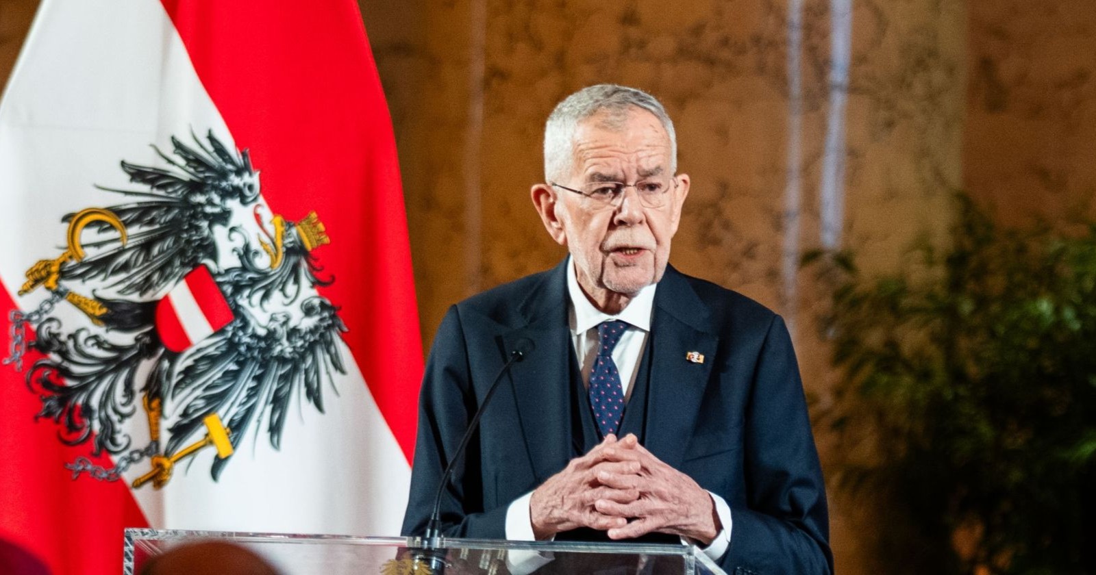 Alexander Van der Bellen spricht beim Neujahrsempfang in der Hofburg vor der österreichischen Flagge mit Bundesadler.