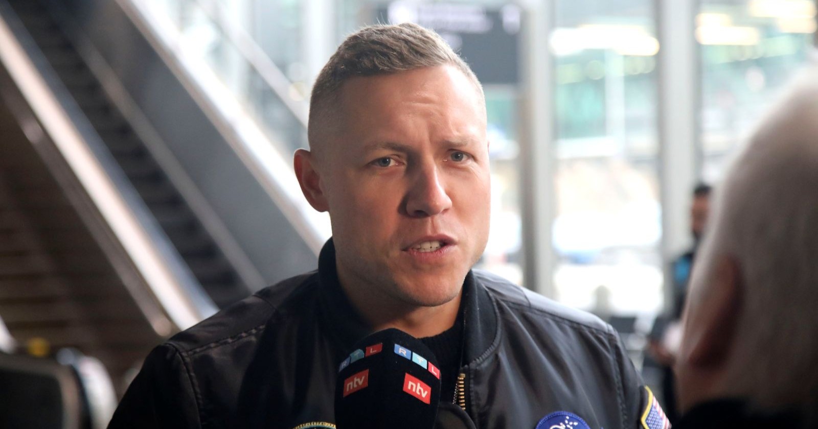 Patrick Romer spricht in ein Mikrophon/Patrick Romer hat einen Käfer ins Feuer geworfen