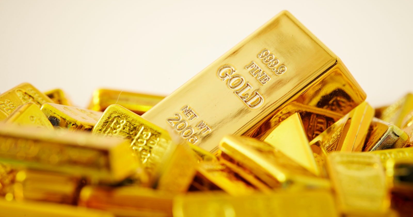 Eine große Anzahl Goldbarren liegt vor einem hellen Hinergrund