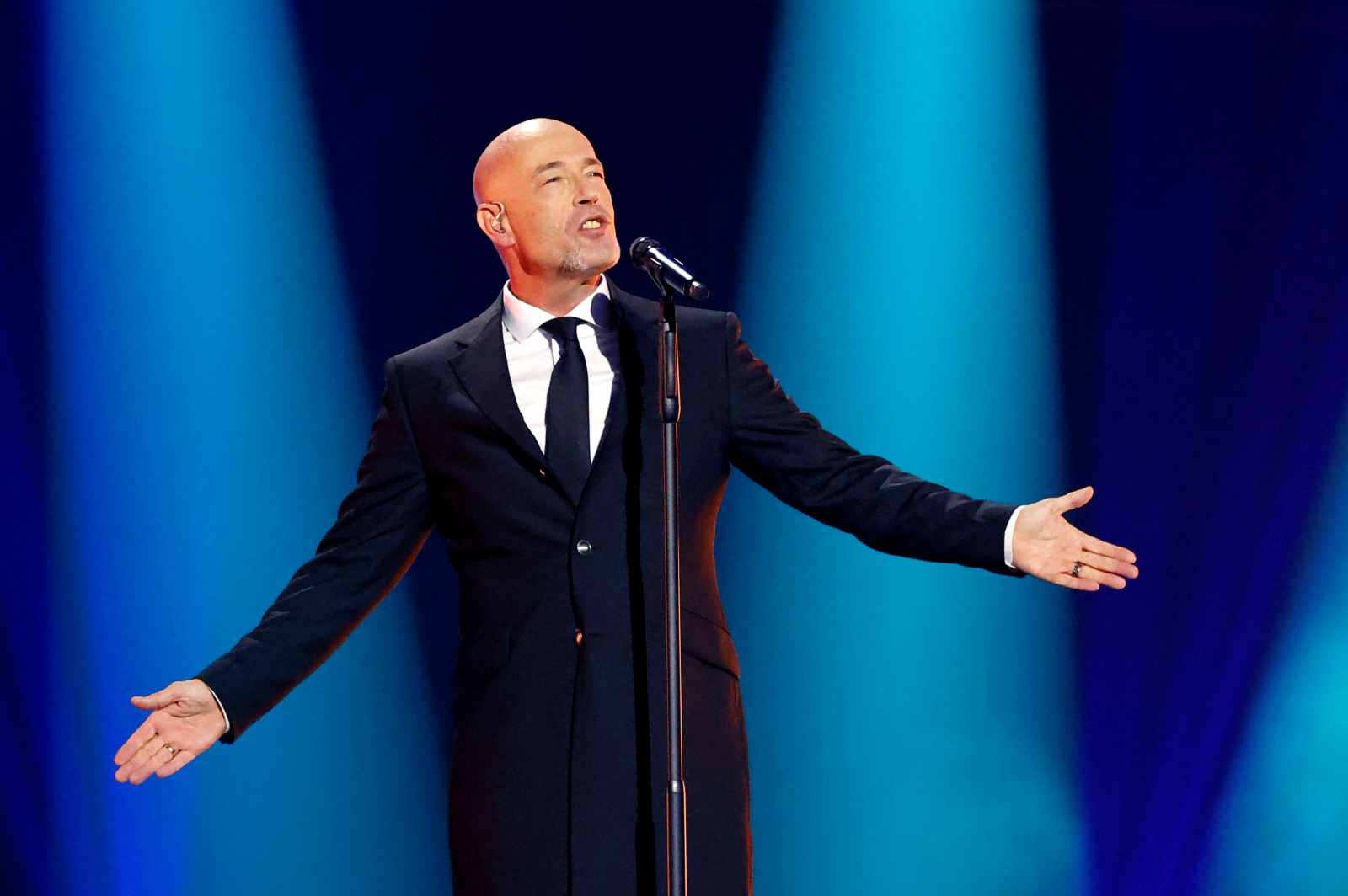 Der Graf von Unheilig steht im schwarzen Anzug auf der Bühne und singt ins Mikrofon, die Arme ausgebreitet.