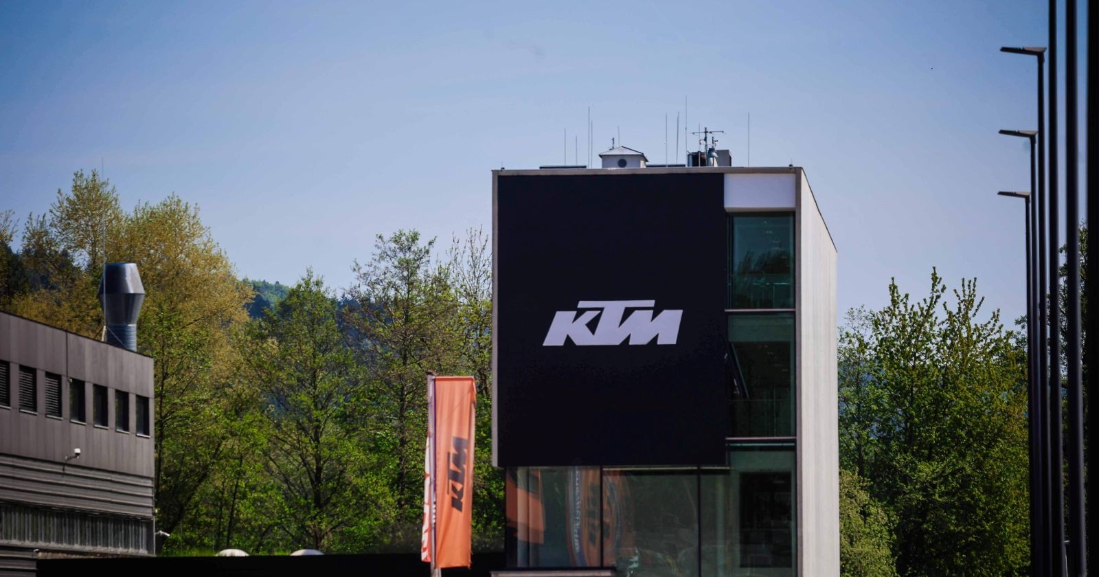 KTM-Firmengebäude in Mattighofen mit großem KTM-Logo an der Fassade und orangen Fahnen vor dem Gebäude.