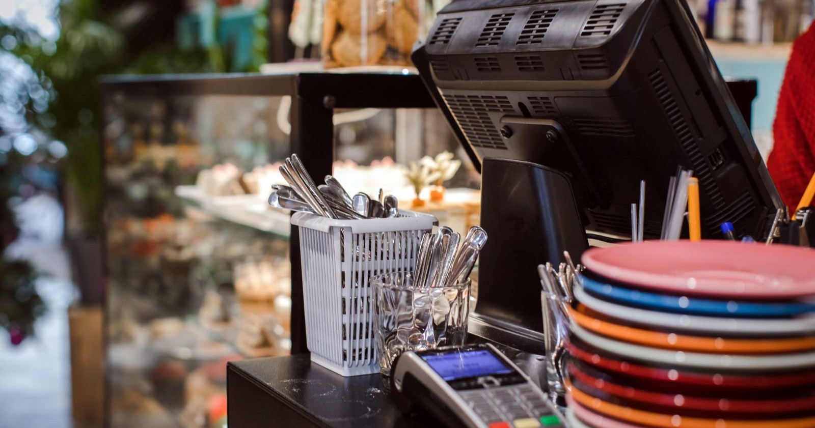 Registrierkasse in einem Gastronomiebetrieb mit Tellerstapel und Kartenterminal – Symbolbild für Registrierkassen in der Gastronomie.