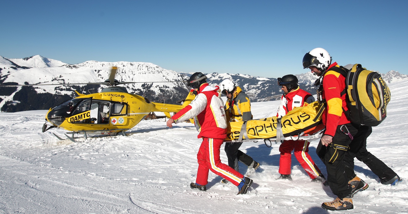 Heli und Rettungskräfte bergen einen Skifahrer auf einem Berg.