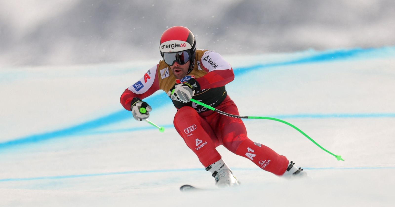 Vincent Kriechmayr in rotem Rennanzug während der Abfahrt in Wengen, konzentriert in tiefer Position auf der eisigen Piste.