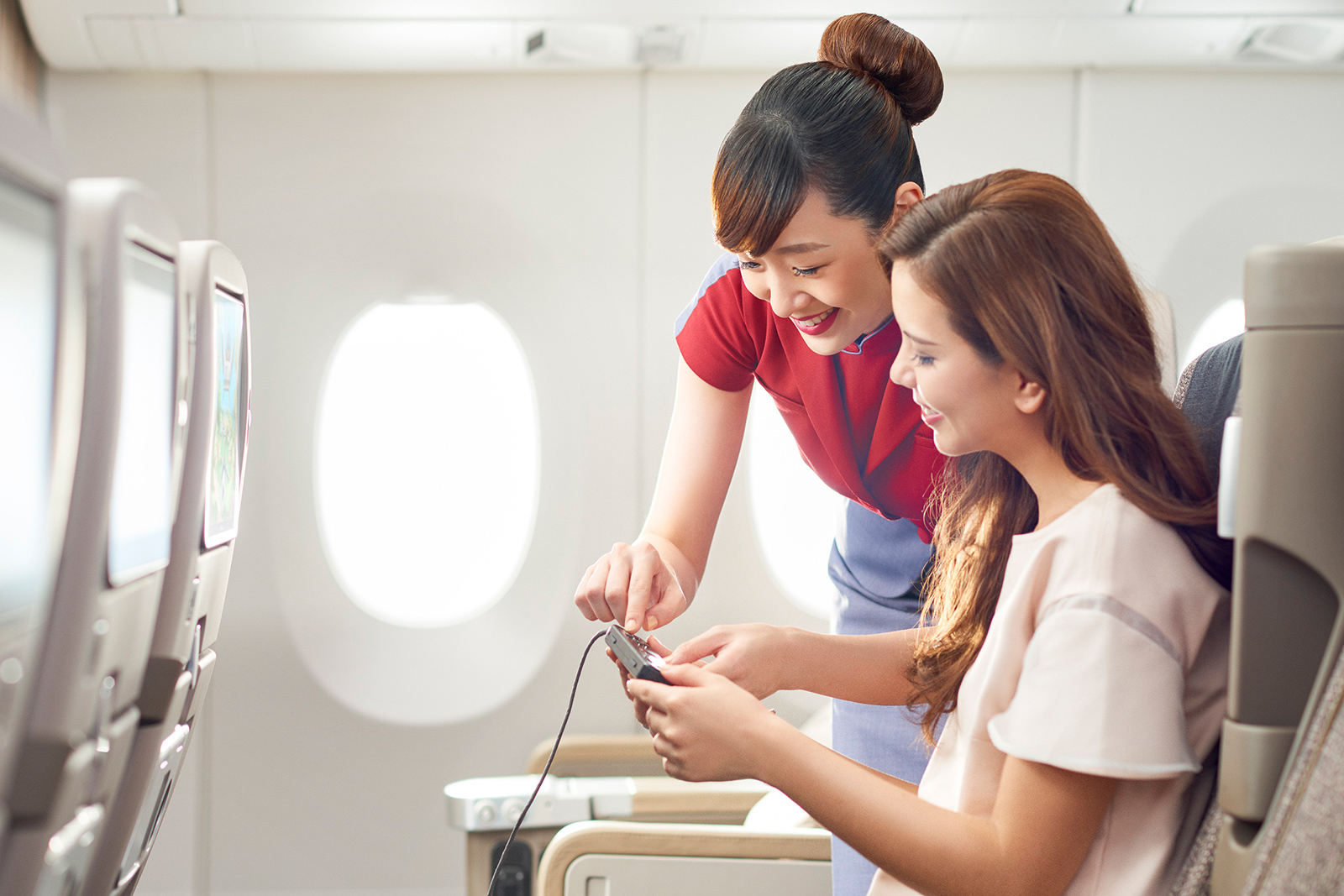 Stewardess hilft weiblichem Fluggast beim Entertainment-Programm | Credit: China Airlines Taiwan
