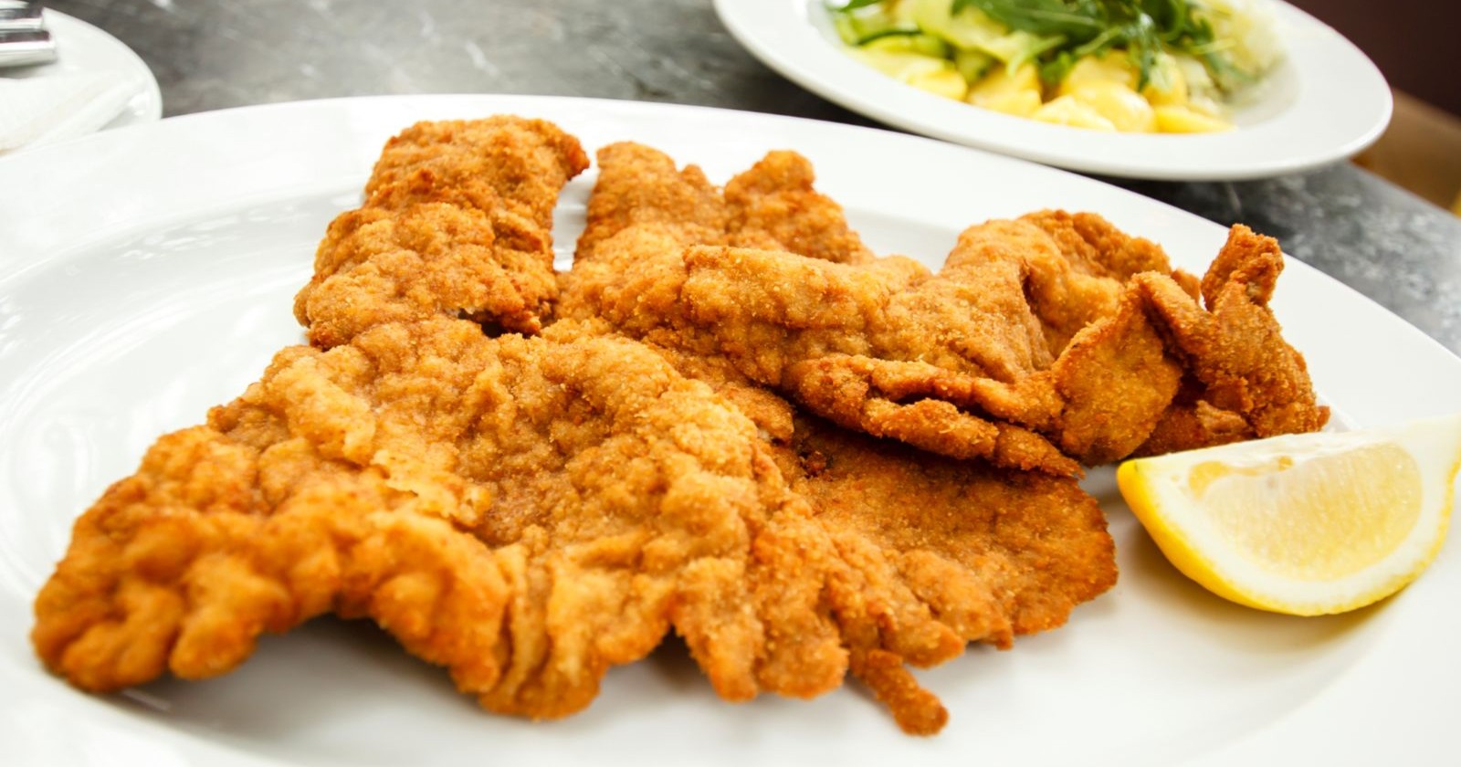 Wiener Schnitzel mit Zitronenspalte auf weißem Teller – Symbolbild zur Insolvenz des Kärntner Gastronomen Dietmar Ronacher in Völkermarkt.