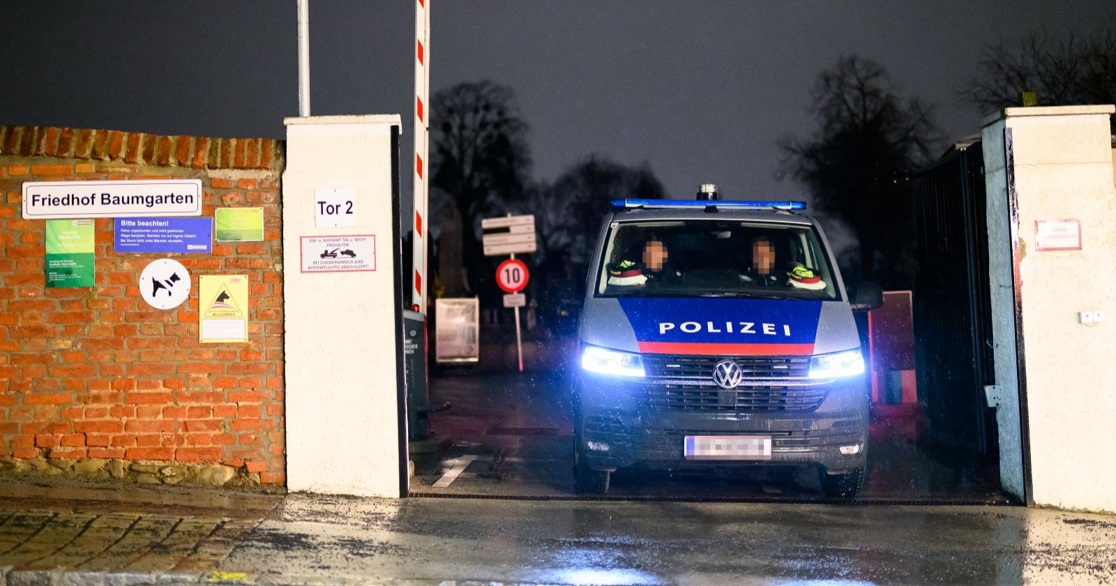 Ein Polizeifahrzeug steht am Eingang des Friedhofs Baumgarten in Wien-Penzing bei Nacht, wo eine Frau erstochen wurde.