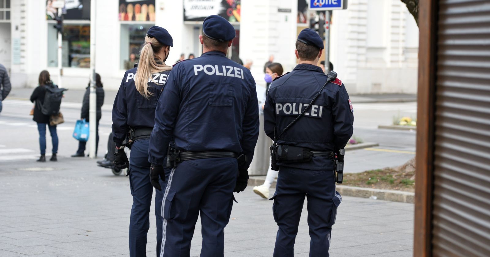 Drei Polizistinnen und Polizisten in Uniform stehen in einer Wiener Innenstadtstraße und beobachten den Einsatzbereich – Themenbild für zwei Kinder, die in Wien vermisst wird.