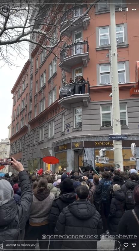 Menschenmenge auf der Wiener Mariahilferstraße blickt zu einem Balkon hinauf,wo Maxamillion