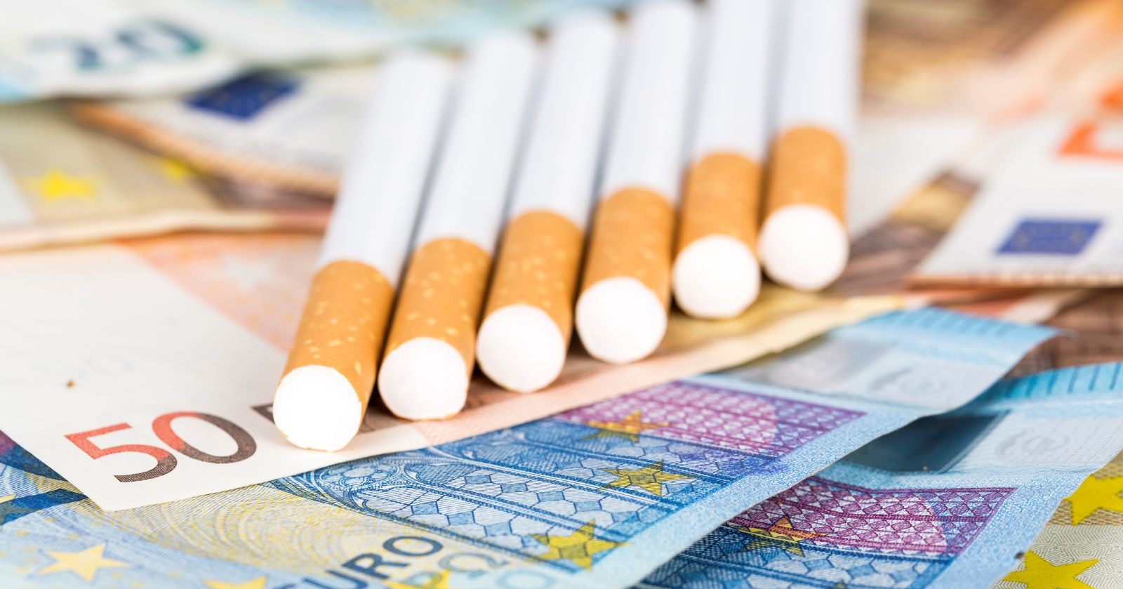 Mehrere Zigaretten liegen auf Euro-Banknoten und symbolisieren die steigenden Tabakpreise in Österreich im März 2026.