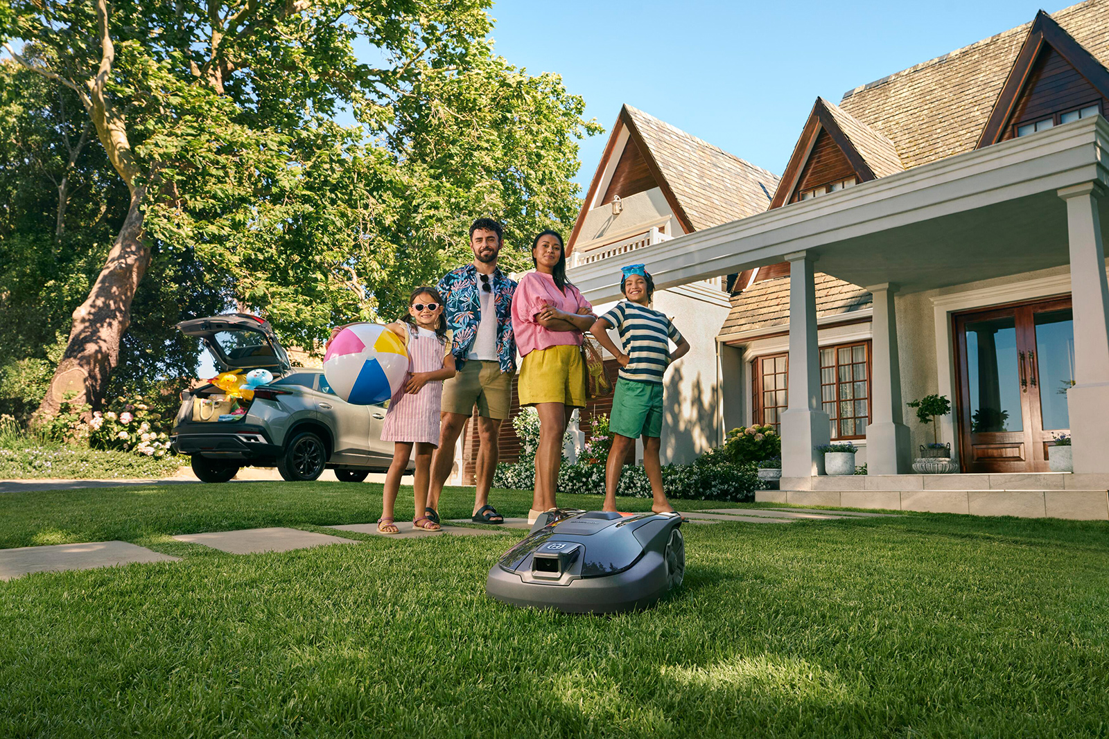 Glückliche Familie mit Mähroboter im Garten | Credit: Husqvarna