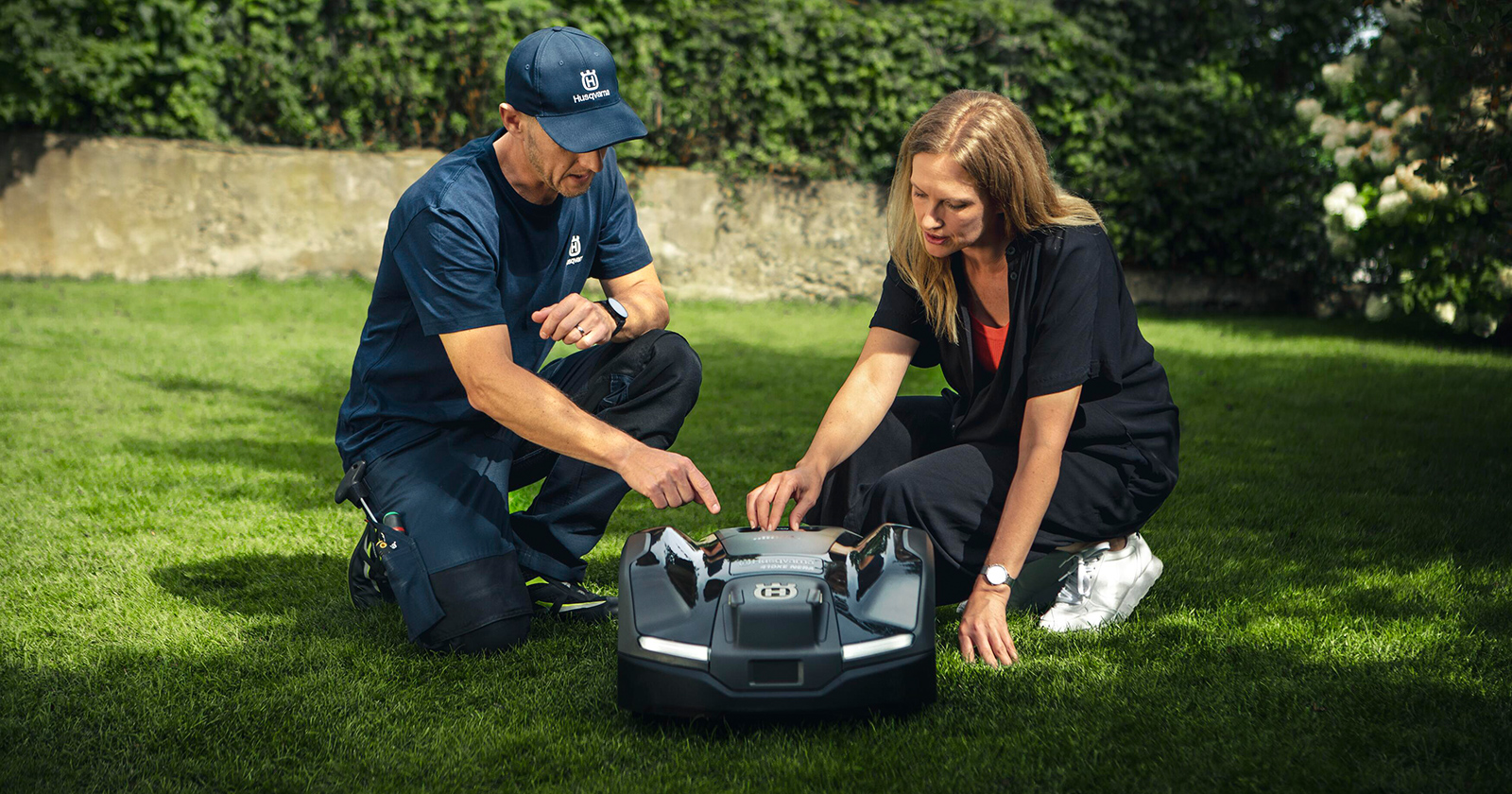 Kundenberater erklärt Frau einen Mähroboter | Credit: Husqvarna