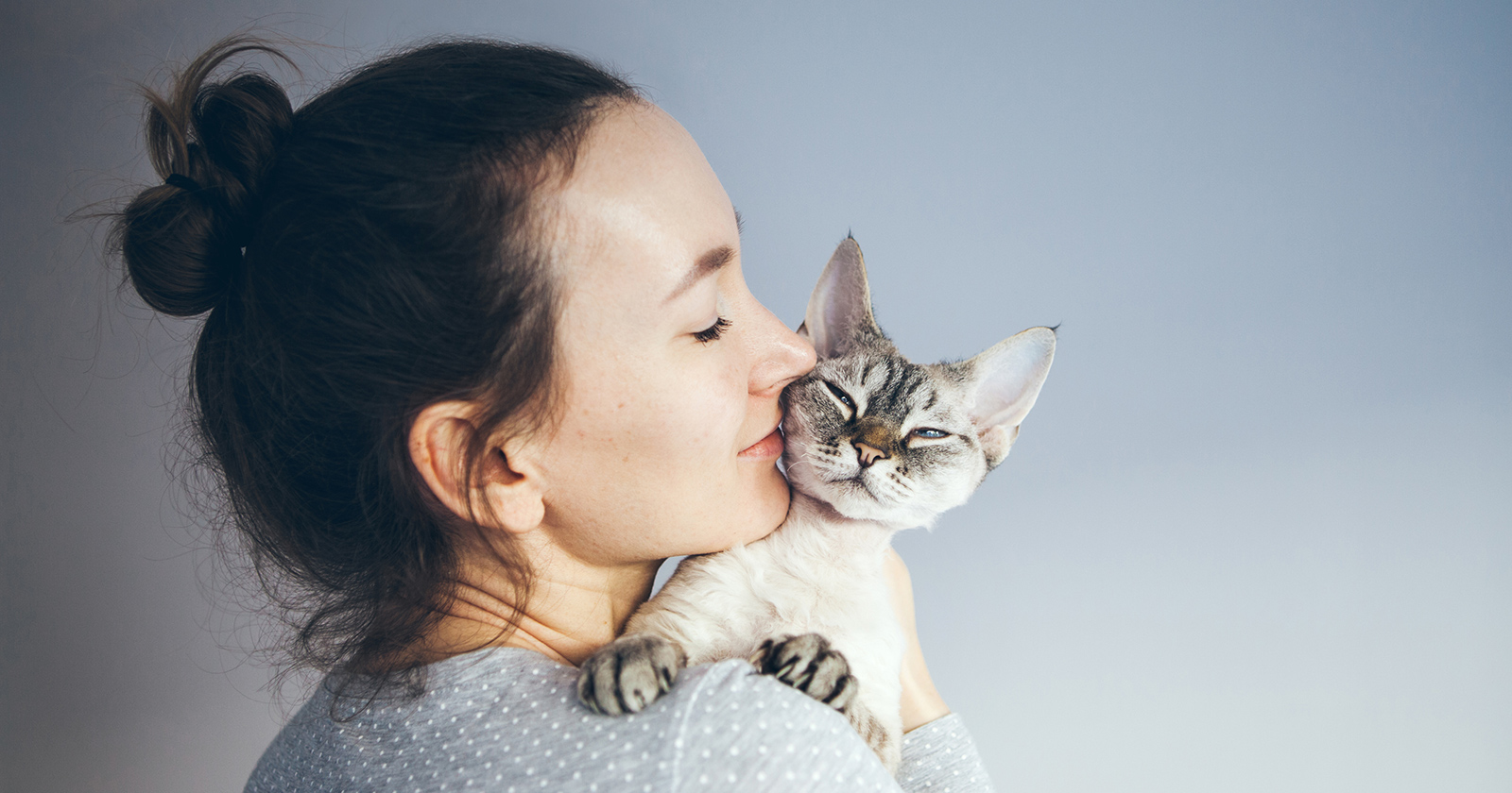 Junge Frau kuschelt mit ihrer Katze | Credit: iStock.com/insonnia