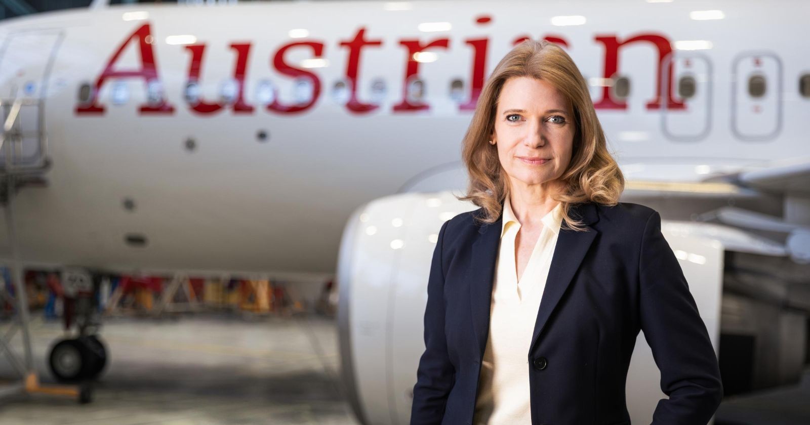 Frau im dunklen Blazer vor einem Flugzeug