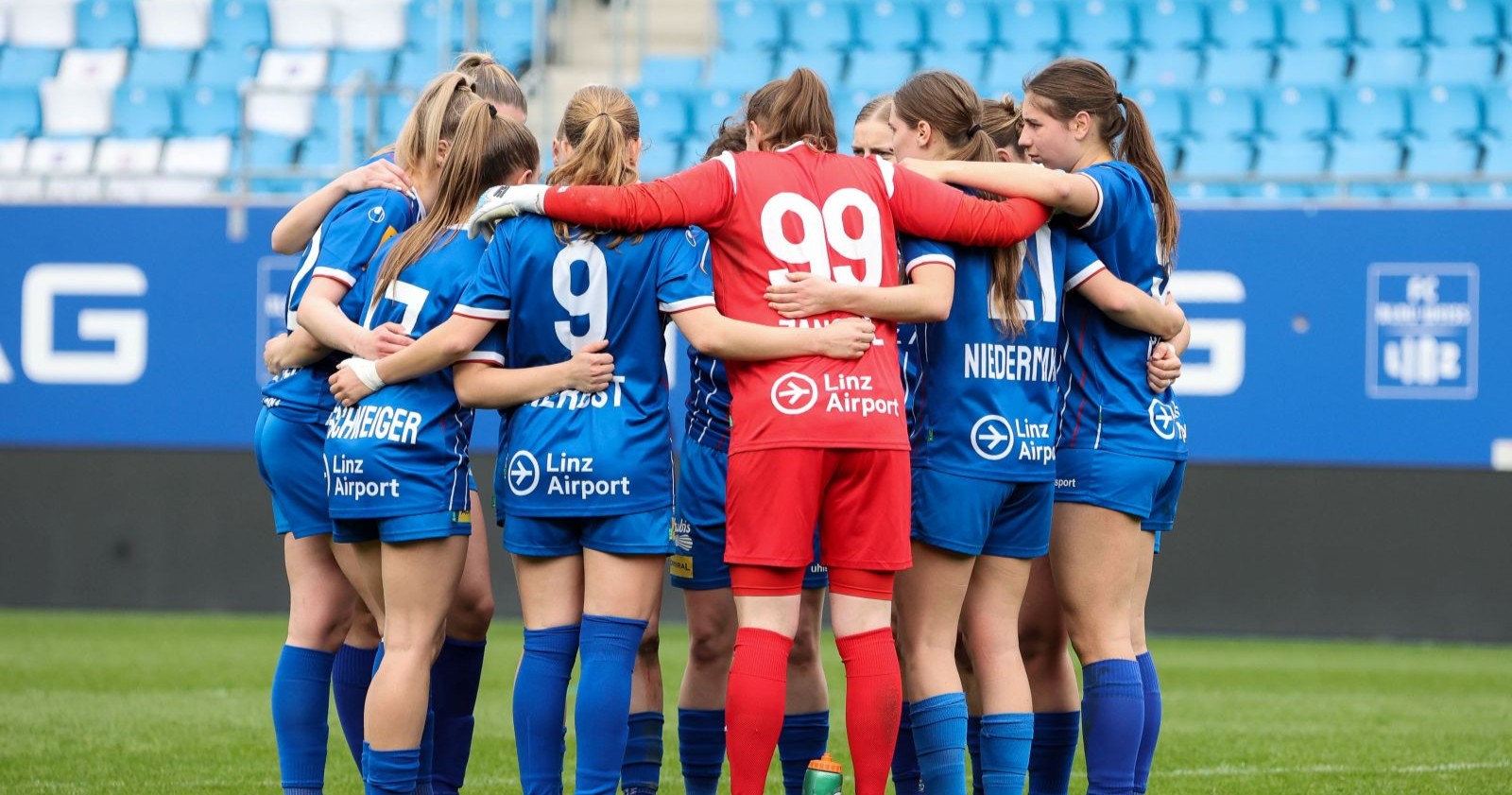 Mehrere Fußballerinen bilden einen Kreis und legen die Arme übereinander